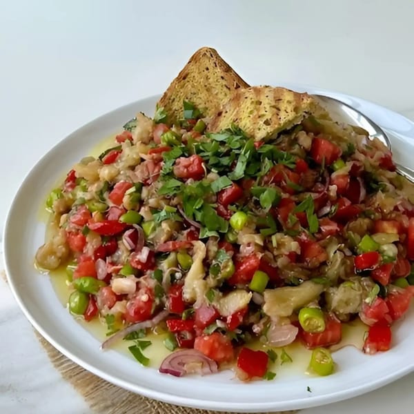 A vibrant salad with chopped tomatoes, green peppers, onions, and herbs, served with toasted bread.